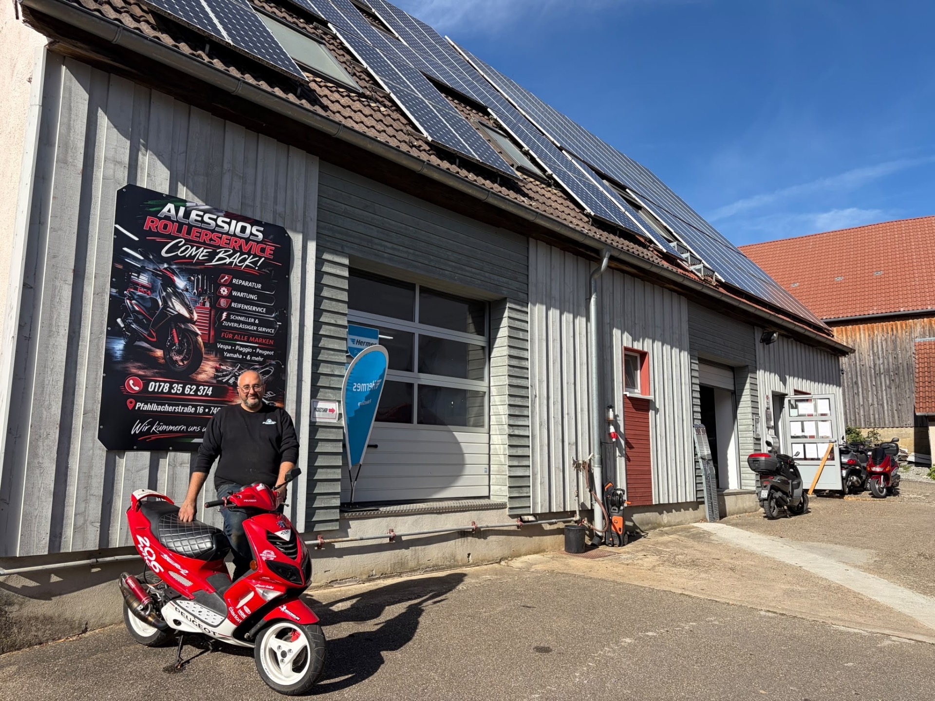Inhaber von Alessios Rollerservice mit rotem Roller vor dem Betriebsschild in Zweiflingen